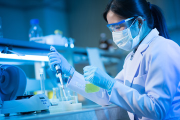 Young female scientist or researcher in medical lab with test tube centrifuge and flask