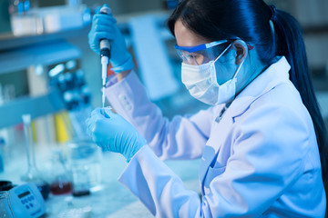 Young female scientist or researcher in medical lab with test tube centrifuge and flask