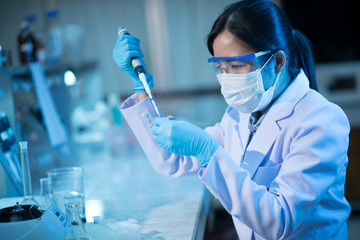 young female scientist or researcher in medical laboratory with test tubes and auto pipette