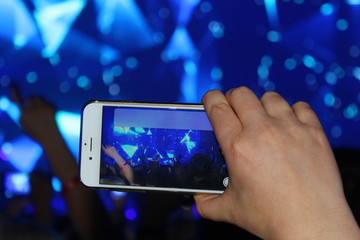 at the concert the hand holds the phone and take the scene
