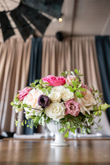 Arrangement of fresh flowers in pastel colors with a bright accent. Wedding background. table in a restaurant. different varieties of garden and shrub roses in a light vase on wooden table