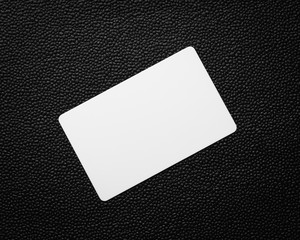 White card on dark leather background. Blank business card.