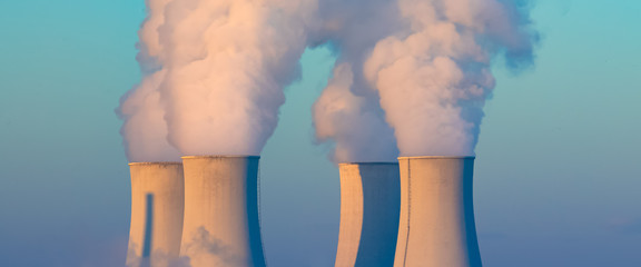 cooling towers with water steam in morning light, nuclear plant