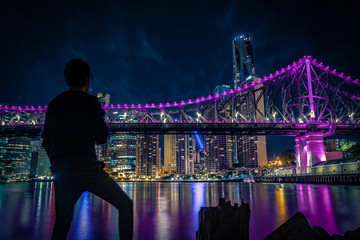 Fototapeta na wymiar Anonymous man looking at bridge and metropolis at night