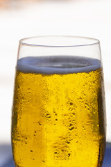 a glass of cold beer with bubbles, different nuts, hot summer day on an outdoor terrace in a bar by the sea