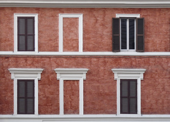 Fototapeta na wymiar different open and closed Windows with shutters on the background of the red wall - in the eternal city of Rome in Italy