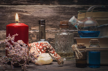 Magic potion in the vial on the wizard table. Witchcraft concept. Essential oil bottles and old books. Herbal medicine.