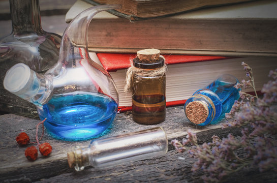 Essential oil bottles and old books. Herbal medicine. Magic potion in the vial on the wizard table. Witchcraft concept.
