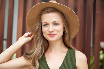 Beautiful stylish young woman in straw hat smiling at camera