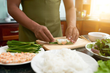 Man making delicious spring rolls with shrimp and vegetables