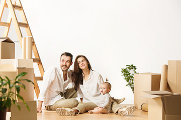 Couple moving to a new home. Happy married people with newborn child buy a new apartment to start...