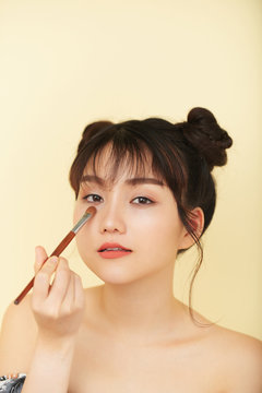 Attractive young Vietnamese woman applying eyeshadow on lower lash line