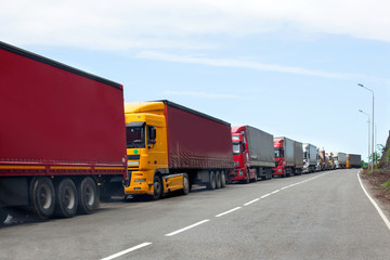 Queue of trucks passing the international border, red and different colors trucks in traffic jam on...