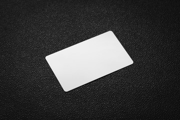 White card on dark leather background. Blank business card.