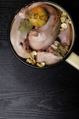 raw pork or beef tongues with black pepper, onion, cress salad in pan on black wooden table, gourment food conception