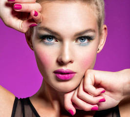Beautiful woman face with blue makeup of eyes and pink nails