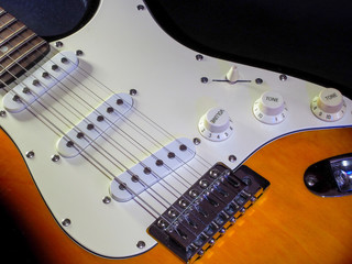 Electric guitar of dark color with light inserts with metal strings