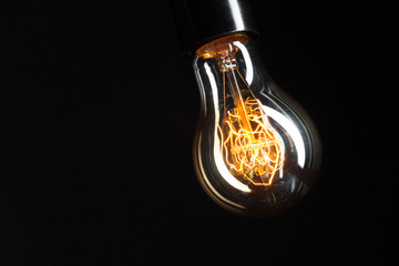 A classic Edison light bulb on dark background with space for text