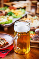 A glass of light beer on the background of a table with snacks.