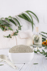 Preparing cosmetic mud mask with various skincare products. Dry clay powder in bowl. Natural cosmetics for home or salon spa treatment. On white background.