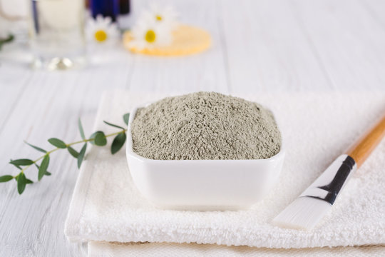 Preparing cosmetic mud mask with various skincare products. Dry clay powder in bowl. Natural cosmetics for home or salon spa treatment. On white background.
