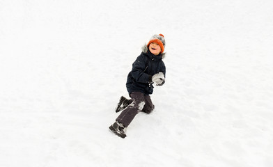 Fototapeta na wymiar childhood, leisure and season concept - happy little boy playing with snow in winter