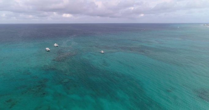 Aerial view of turquoise ocean water with reef and people snorkeling next to the boats