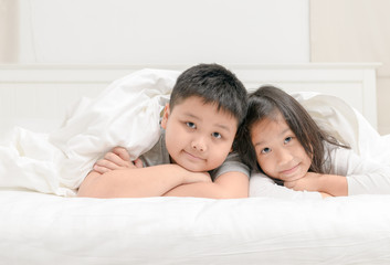 Obraz na płótnie Canvas Two happy sibling children lying under blanket