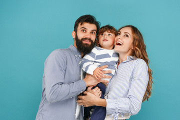 A happy family on blue studio background. The father, mother and son posing together