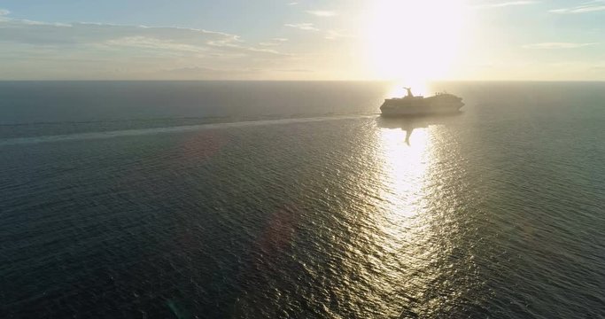 Aerial view of cruise ship silhouette in open ocean at sunset