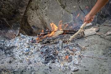 Breeding a fire on an old ashes on a sandy beach in the mountains