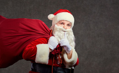 Santa Claus with a bag of gifts on a background for text.