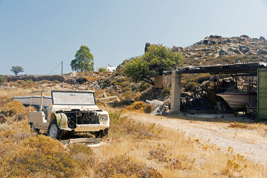 A view of a wrecked car and a baot in the land of Patmos, Greece in summer