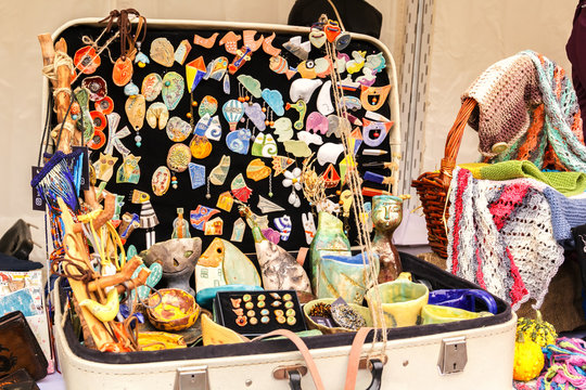 Badges, souvenirs, ceramics and other rubbish in an old shabby suitcase are on display for sale on a street tray