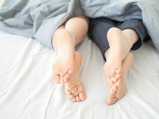 Close-up of the feet of a couple on the bed.