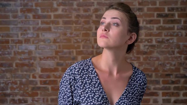 gorgeous caucasian girl is looking around in red brick stodio with relaxed chill face