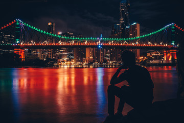 Fototapeta na wymiar Silhouette of man near river in night city