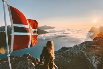Woman enjoying sunset mountains view  and Norway flag on the top traveling lifestyle hiking...