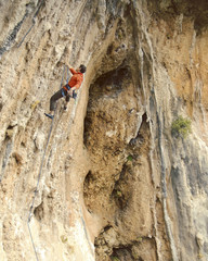 Man rock climber. Rock climber climbs on a rocky wall. Man makes hard move.