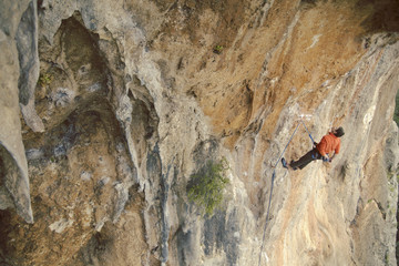 Man rock climber. Rock climber climbs on a rocky wall. Man makes hard move.