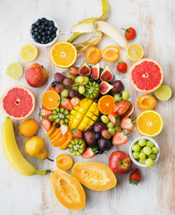 Rainbow fruitsVariety of cut fruits and berries platter, strawberries blueberries, mango orange, apple, grapes, kiwis on the white wood background, copy space for text, layout, t berries on white wood