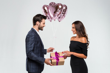Happy birthday my love! Young handsome men giving a gift box to his girlfriend while standing against white background