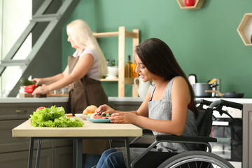 Young woman in wheelchair eating at home