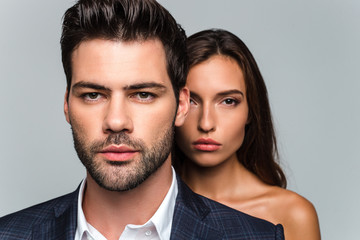 Looking at one side together. Portrait of young beautiful couple looking at camera while standing against white background