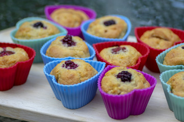 Banana muffins with chocolate, blackberries, strawberries, nuts and raisins in silicone molds on wooden mat, colorful hearts