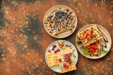 Delicious waffles with berries on plates, top view