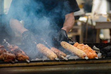 Closeup of man cooking meat on skewers on street festival
