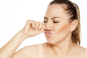 A young woman has itching in the nose on white background