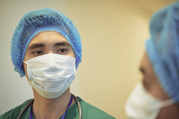 Young Asian surgical intern listening to advice of his coworker