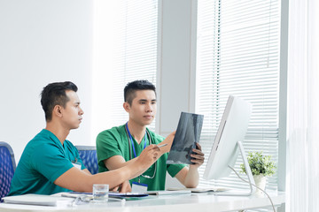 Team of surgeons duscissing fracture x-ray in light office